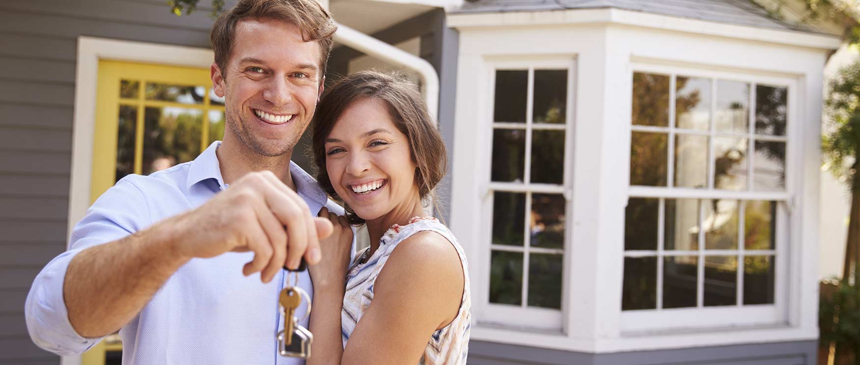 young couple in front of new home
